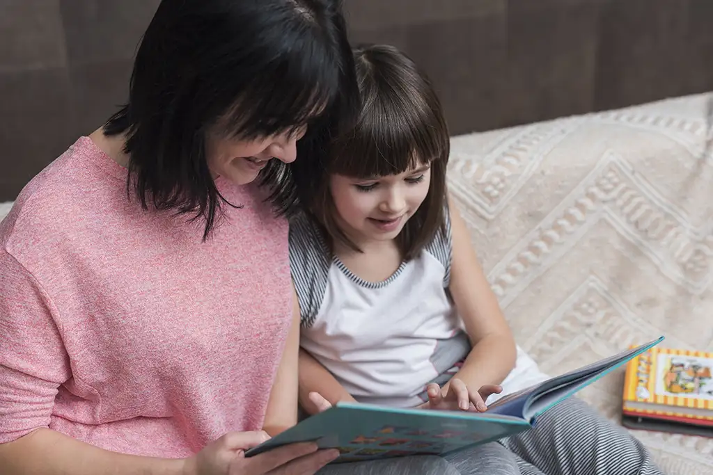 Mother and Daughter Reading a Book on a couch