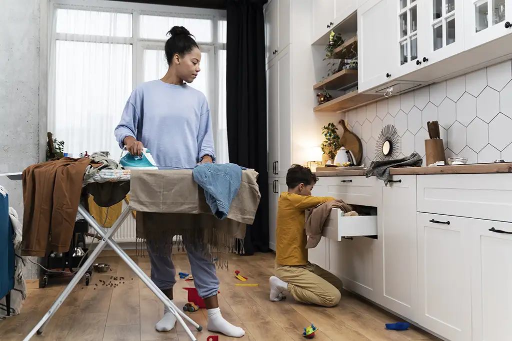 Photo of Woman Ironing and Boy putting away clean clothes